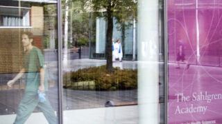 Man walking behind glass door next to a Sahlgren Academy poster