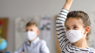 A girl raises her hand in a classroom.