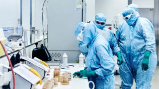 Scientists in protective gear working in a cell laboratory.